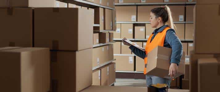 A young woman working in a warehouse wearing a hi vis vest